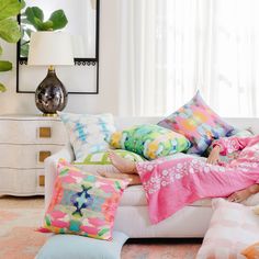 a woman laying on a couch covered in colorful pillows and blankets with her legs crossed