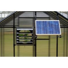 a green house with a solar panel on the roof and a fan in front of it