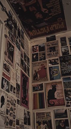 a wall covered in posters and pictures next to a toilet