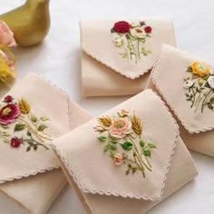 four embroidered napkins with flowers on them