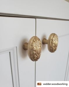 a close up of two knobs on a white cabinet with gold handles and an ornate design