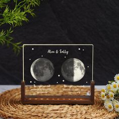 a couple of moon pictures sitting on top of a wooden stand next to some daisies