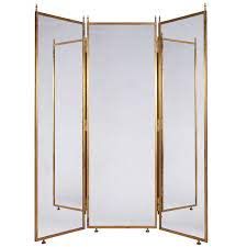 an open folding screen with gold trimmings on the sides and two mirrors behind it