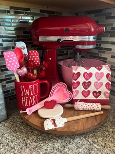 a kitchen counter with red appliances and hearts on the mugs, spoons, and other items