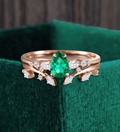 a close up of a ring on a green velvet cushion with diamonds and an emerald stone