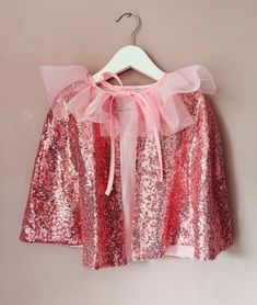 a pink and red sequin top hanging on a wall