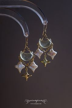 ---- Welcome to CiaoQiao Shop ----- Illuminate your style with the ethereal beauty of our "Enchanted Celestial Charm Earrings." Carefully crafted to capture the whimsical allure of a starry night, these earrings feature genuine baroque pearls fashioned into delicate stars, each one unique in its luster and form. Dangling gracefully from a chain of gold, they accompany a golden crescent moon, creating a celestial dance of elegance and charm. The stars and moon are suspended from a fine gold-tone Porcelain Hand Jewelry, Dangle Earring Display, Celestial Diamond Jewelry, Fancy Jewellery Earrings, Ethereal Earrings, Gold Star Jewelry, Whimsical Earrings, Upcycled Earrings, Ethereal Jewelry