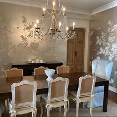 a dining room table with chairs and chandelier in front of a wall mural