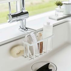 a sink with soap, toothbrushes and other bathroom items in it next to a window