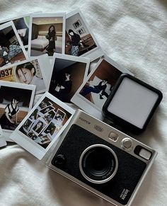 an old camera and some polaroid pictures on top of a white bed sheet,