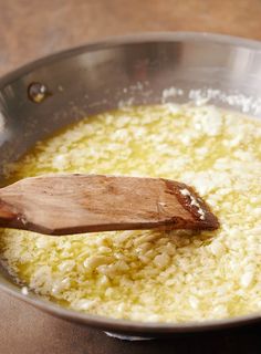 a wooden spoon stirring rice in a pan