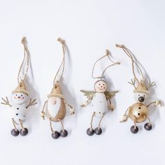 three christmas ornaments hanging from twine with bells and snowmen on them, all decorated in gold and white