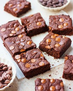 chocolate brownies are cut into squares and placed on a table with bowls of chocolate chips