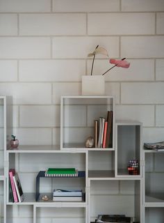 a white shelf with books and a flower on top