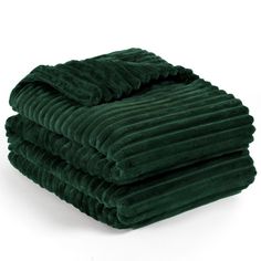 three green blankets stacked on top of each other in front of a white background,