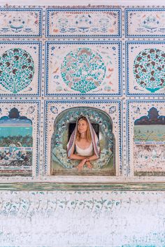 a woman sitting in the window of a building with blue and white tiles on it