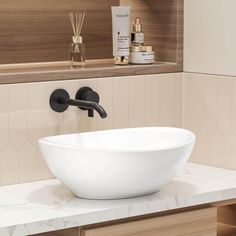 a white bowl sink sitting on top of a counter next to a mirror and bottles