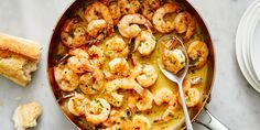 a skillet filled with shrimp next to bread