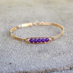 A sweet little bracelet of five strands of 14kt gold filled wire with a center design featuring five 4mm genuine amethyst beads and accented with two smaller beads. Perfect for that February birthday girl! Stackable, too, along with many of my other wirewrapped bracelets! The sturdy built-in hook and eye clasp is easy to get on and off by yourself. Choose the size you need for a comfortable custom fit. Also available in sterling silver. Dainty Hand Wrapped Gold Beaded Bracelets, Dainty Hand-wrapped Gold Beaded Bracelets, Gold Hand-strung Wrap Bracelet Gift, Gold Wire Wrapped Bracelets In 14k Gold Filled, Wire Wrapped 14k Gold Filled Bracelets, Gold Wire Wrapped 14k Gold-filled Bracelets, Adjustable Hand-strung 14k Gold Filled Bracelet, Adjustable 14k Gold-filled Jubilee Bracelet, Dainty Hand Wrapped Gold Bracelet