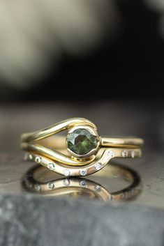 two gold rings with a green stone in the middle