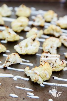 cauliflower sprinkled with white sauce sitting on top of a baking sheet