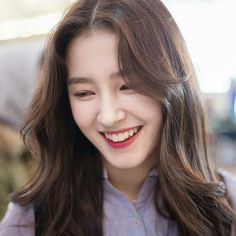 a woman with long brown hair smiling at the camera