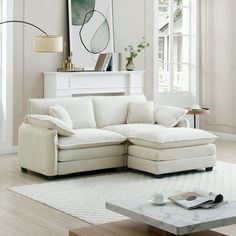 a living room with a white sectional couch and coffee table in front of a large window