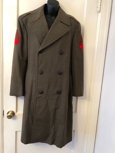 Vintage Wool Green Military Heavy Overcoat with belt and double breast buttons in front.  This is an old overcoat and does have some places where moths might have done some damage.  It is small pin hole areas and on the back of the coat is a larger place, in fact several places.  On the front below the double breast buttons is another place.  Please look at all of the pictures as part of the description.  This coat is very heavy, therefore the shipping is what it is.  Measurements:  Taken from seam to seam while the garment is lying flat.  Double armpit.                              Length:  Top of shoulder to hem of coat is 42 inches                              Sleeves:  From top of shoulder to the end of the sleeve:  24 inches                              Across under arms:  Armpit to A Uniform Style Long Coat With Buttons, Military Double-breasted Pea Coat With Buttons, Vintage Double-breasted Pea Coat With Double Button Closure, Vintage Double-breasted Pea Coat, Vintage Military Outerwear With Buttons, Vintage Long Pea Coat With Double Button Closure, Small Pin, Pin Hole, To The End