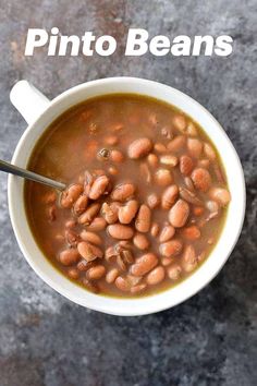 a white bowl filled with beans on top of a gray counter next to a spoon