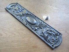 an ornate metal door handle on a wooden table next to some pieces of silverware