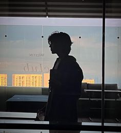 a man standing in front of a window with the reflection of a building behind him