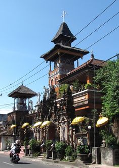 an old building with a clock tower on the top and yellow umbrellas hanging from it's roof