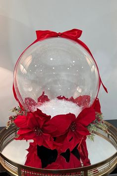 a snow globe with poinsettis in it on top of a basket filled with water