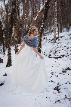 a woman in a white dress is walking through the snow with a scarf around her neck