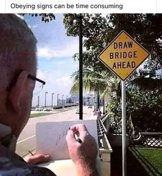 an older man writing on a piece of paper next to a sign that says draw bridge ahead