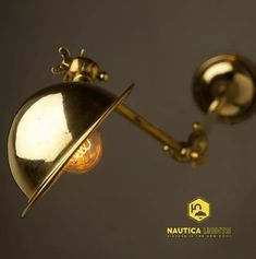 an antique brass wall light on a gray background with the words nautitica lighting above it