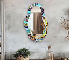 a mirror that is on the side of a wall next to a potted plant