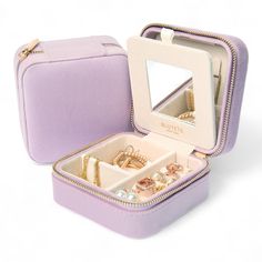 an open purple suitcase with jewelry inside on a white surface and reflection in the mirror