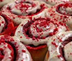 red velvet cinnamon rolls with white frosting and sprinkles on top, ready to be eaten