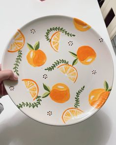 a person holding a plate with oranges painted on it