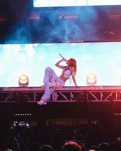 a woman in white outfit sitting on top of a stage