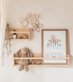 a teddy bear is sitting on a shelf in front of a framed print and some shelves