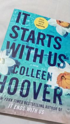 the book it starts with us by collien hoover is sitting on a chair