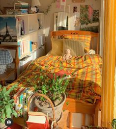 a bedroom with an unmade bed covered in plaid sheets and pillows next to potted plants