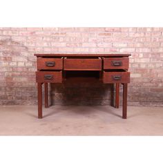 an old wooden desk with two drawers on one side and a brick wall in the background