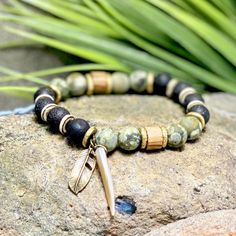 The green beaded bracelet is an authentic piece of Native American jewelry, inspired by nature and crafted in a bohemian style. This spiritual protection bracelet is perfect for men seeking a meaningful and culturally significant accessory. 🪶 𝗠𝗔𝗧𝗘𝗥𝗜𝗔𝗟𝗦 + 𝗗𝗜𝗠𝗘𝗡𝗦𝗜𝗢𝗡𝗦 ❯  10mm Rhyolite, Jasper, Wood, Abalone Shell, Brass ❯  Heavy Duty Elastic Cording 🪶 𝗦𝗧𝗢𝗡𝗘 + 𝗘𝗟𝗘𝗠𝗘𝗡𝗧 𝗘𝗡𝗘𝗥𝗚𝗬 ❯  NUMEROLOGY POWER OF 1 signifying courage, focus, will, and enlightenment ❯  RHYOLITE offers the energy of self-esteem ❯  JASPER clears electromagnetic and environmental pollution ❯  WOOD symbolizes life, growth and strength 🪶 𝗣𝗘𝗥𝗦𝗢𝗡𝗔𝗟𝗜𝗭𝗔𝗧𝗜𝗢𝗡 + 𝗚𝗜𝗙𝗧 𝗦𝗘𝗧 𝗦𝗨𝗚𝗚𝗘𝗦𝗧𝗜𝗢𝗡𝗦 ❯  Add a Wood Bracelet Tray, with or without a monogram + cotton travel bag (photo 7) Handmade Bohemian Bracelets For Meditation, Bohemian Handmade Bracelets For Meditation, Bohemian Gemstone Beads Friendship Bracelets For Beach, Bohemian Friendship Bracelets For Meditation, Handmade Bohemian Stretch Bracelet For Meditation, Bohemian Gemstone Beads Friendship Bracelets, Bohemian Gemstone Beads Bracelets For Beach, Bohemian Green Stretch Bracelet With 8mm Beads, Hippie Green Bracelet Jewelry