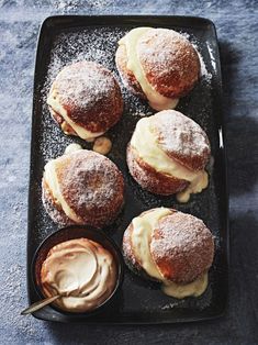 powdered sugar covered pastries on a black tray