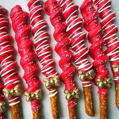 red and white candy canes with gold decorations on them are lined up in rows