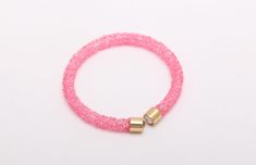 a pink bracelet with two gold clasps