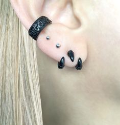 a close up of a person's ear with black stones on it